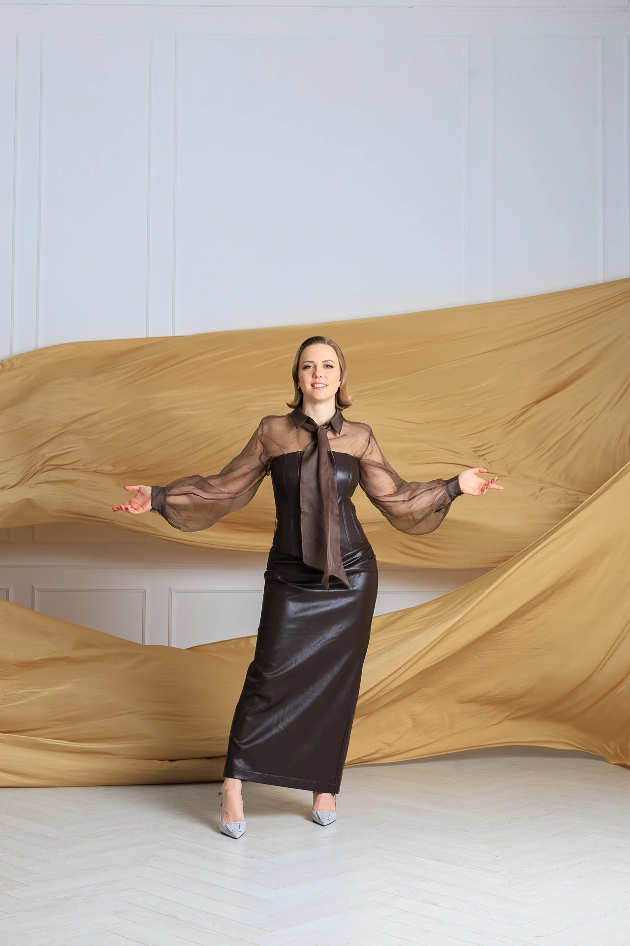 Ирина Кривошей в коричневом платье на фоне золотых полотен ткани