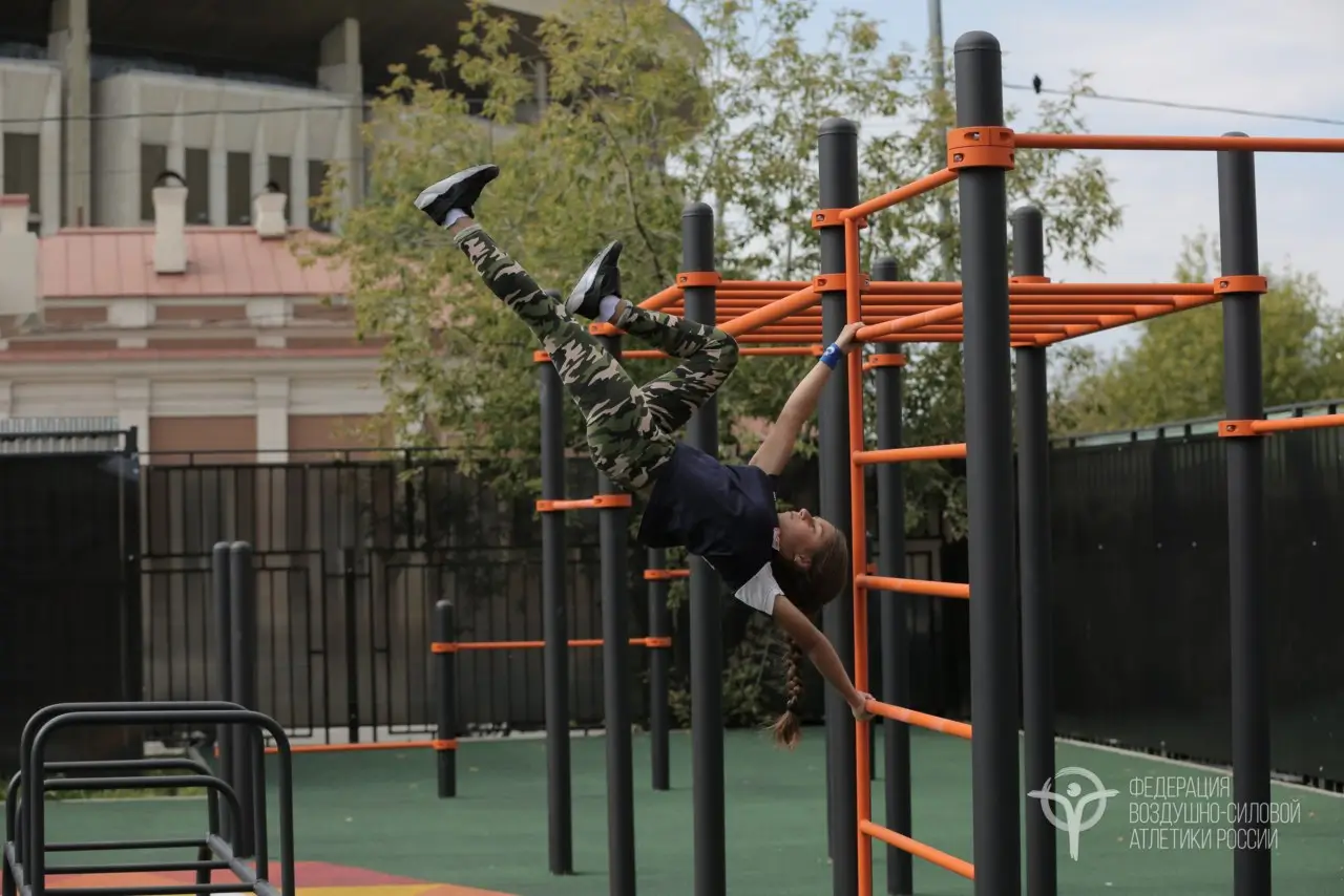 Девочка делает упражнения на воркаут-площадке