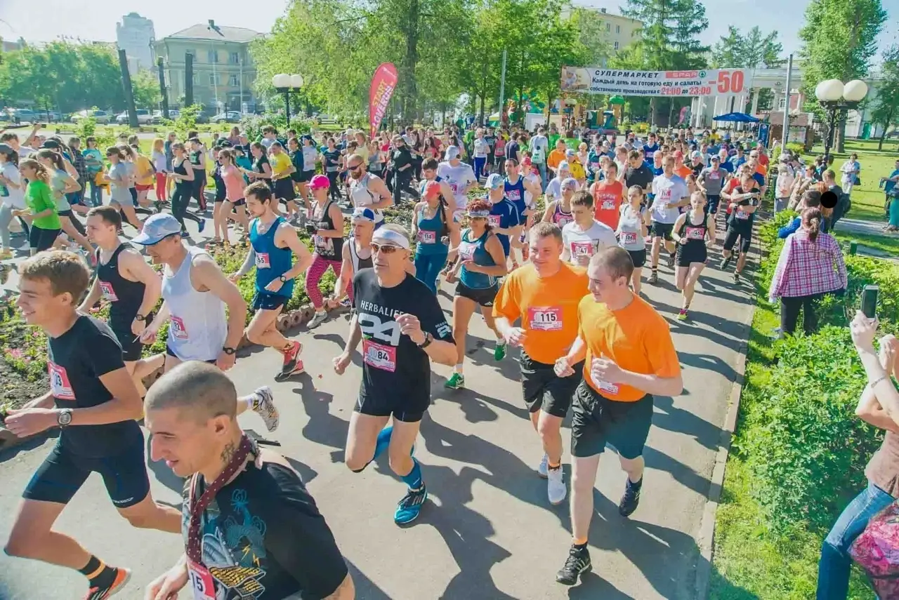 Участники марафона бегут через сквер