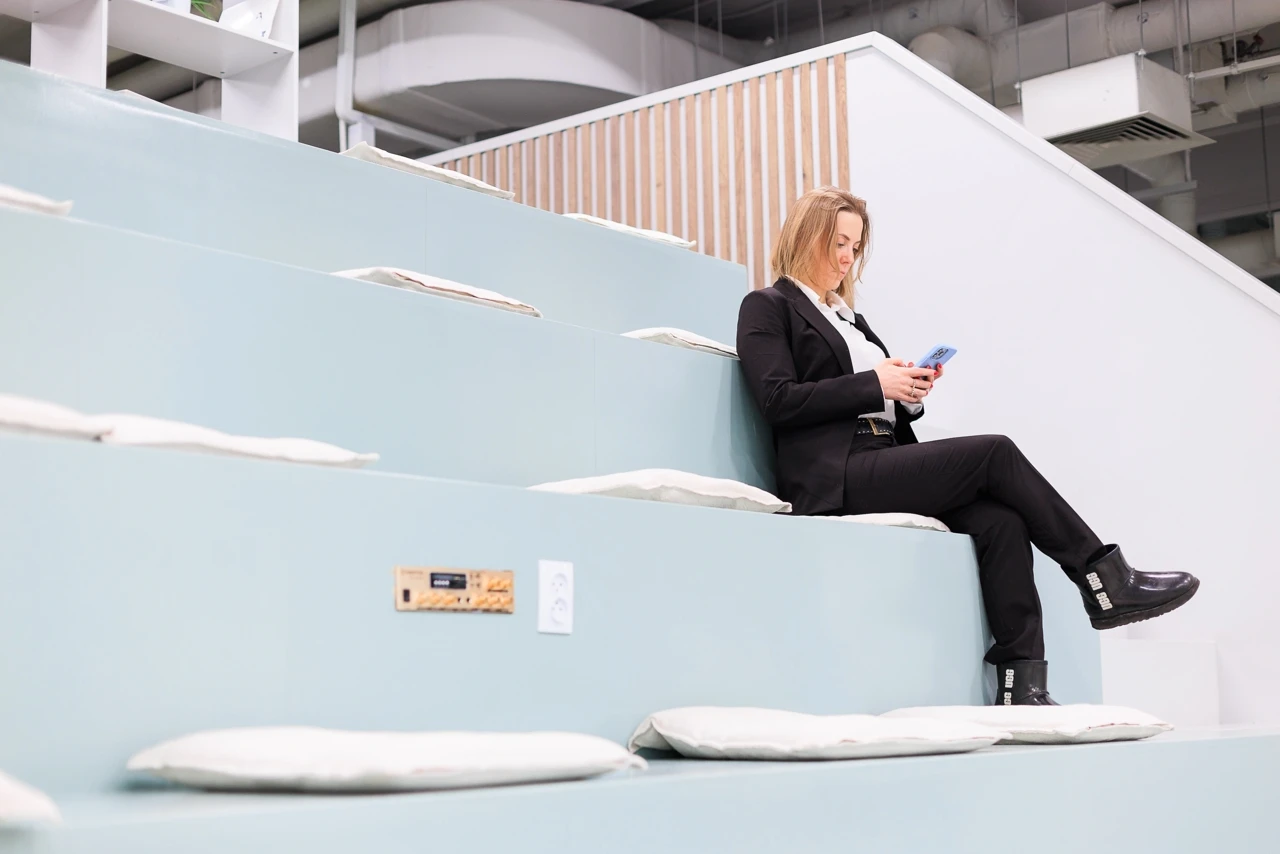 Ирина Кривошей в деловом костюме сидит на ступенях