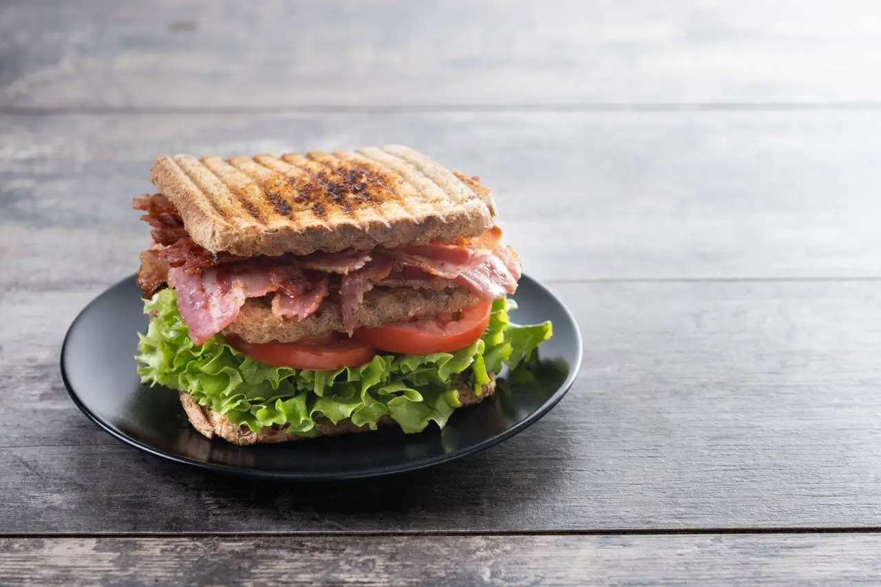 Сэндвич с салатом, беконом и помидором на тарелке